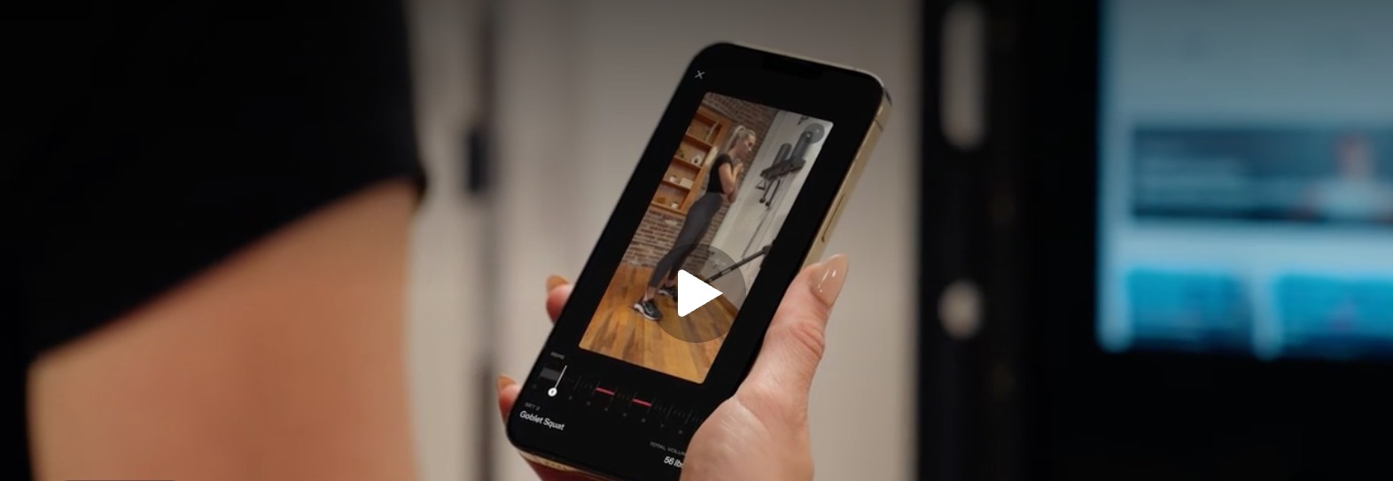 Member holding a phone showing the Smart View camera preview during a Tonal workout